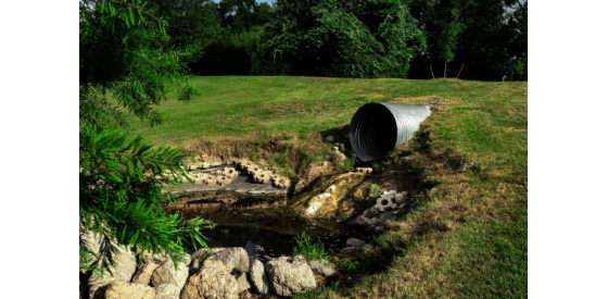 Dirty water flowing from pipe into stream