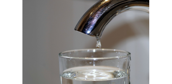 Water dripping from a tap into a glass