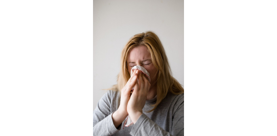 woman sneezing into tissue