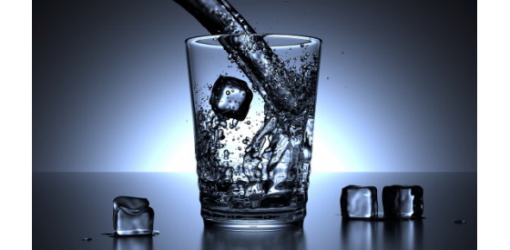 Water pouring into a glass of water full of ice cubes