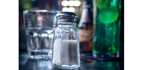 Salt shaker sitting on a table with a blurred restaurant background