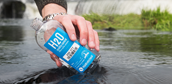 Hand pouring river water into sampling bottle