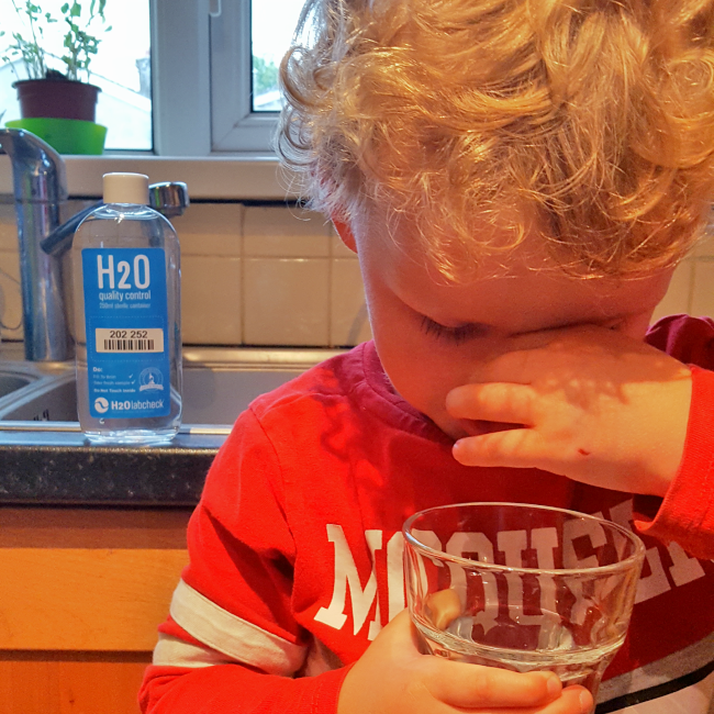 Boy closed his nose because of the smelly water in a glass 