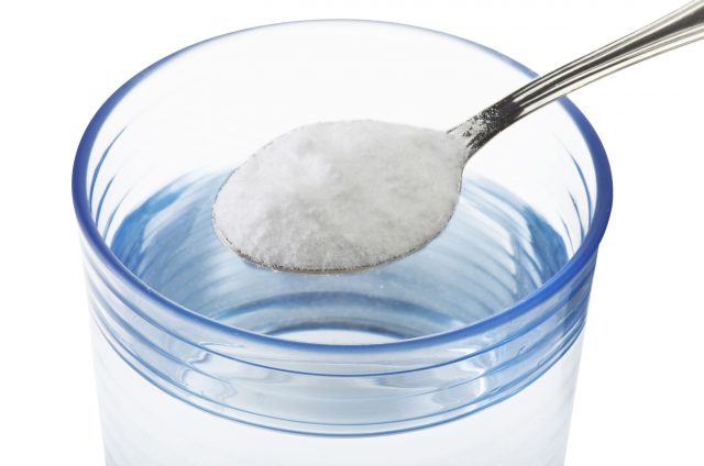 Spoonful of Salt above a glass of water